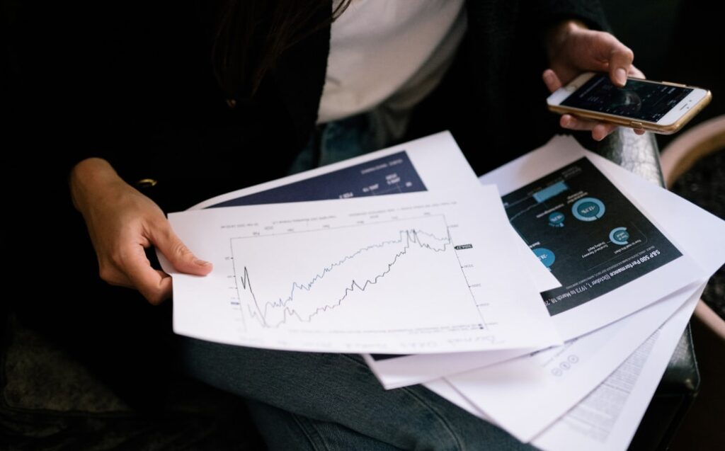 Osoba analyzuje dokumenty a data na mobilním telefonu, související s vyklízecími pracemi a likvidací odpadu.